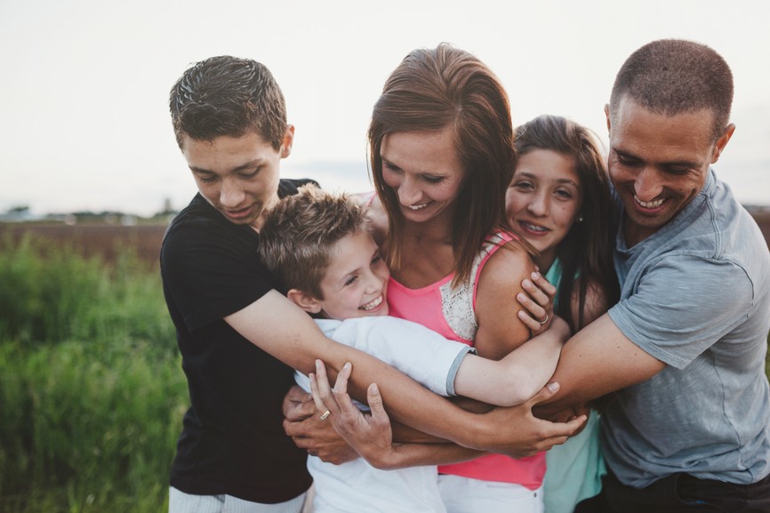 Candid portrait of happy, loving family with teenagers hugging m