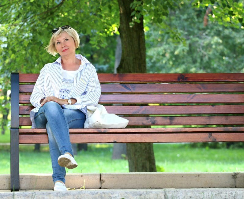 Kobieta siedzi na ławeczce